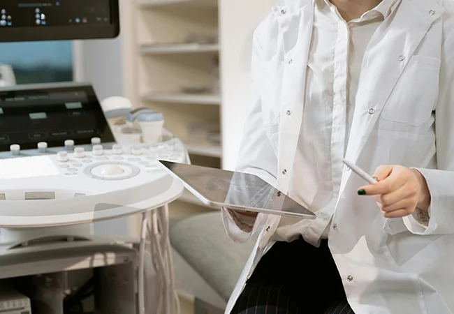 Ein Arzt vor einem Ultraschallgerät sitzend